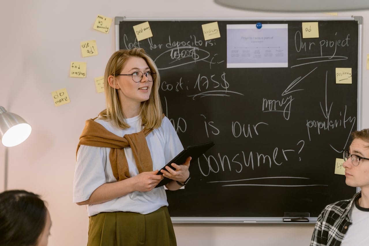 a-woman-in-white-shirt-standing-near-the-chalkboard